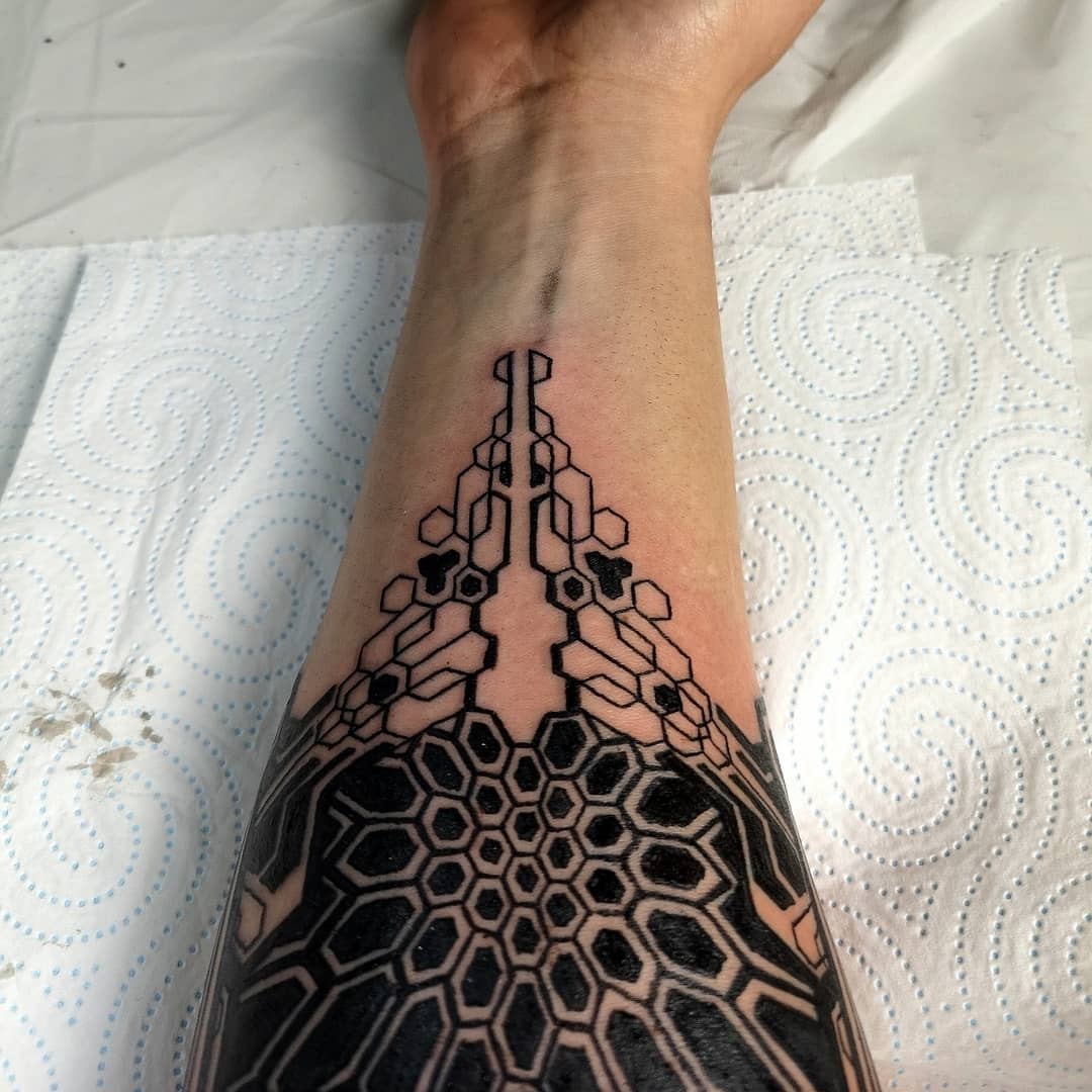 Detailed cyberpunk tattoo on forearm featuring interlocking hexagonal patterns with bold black accents